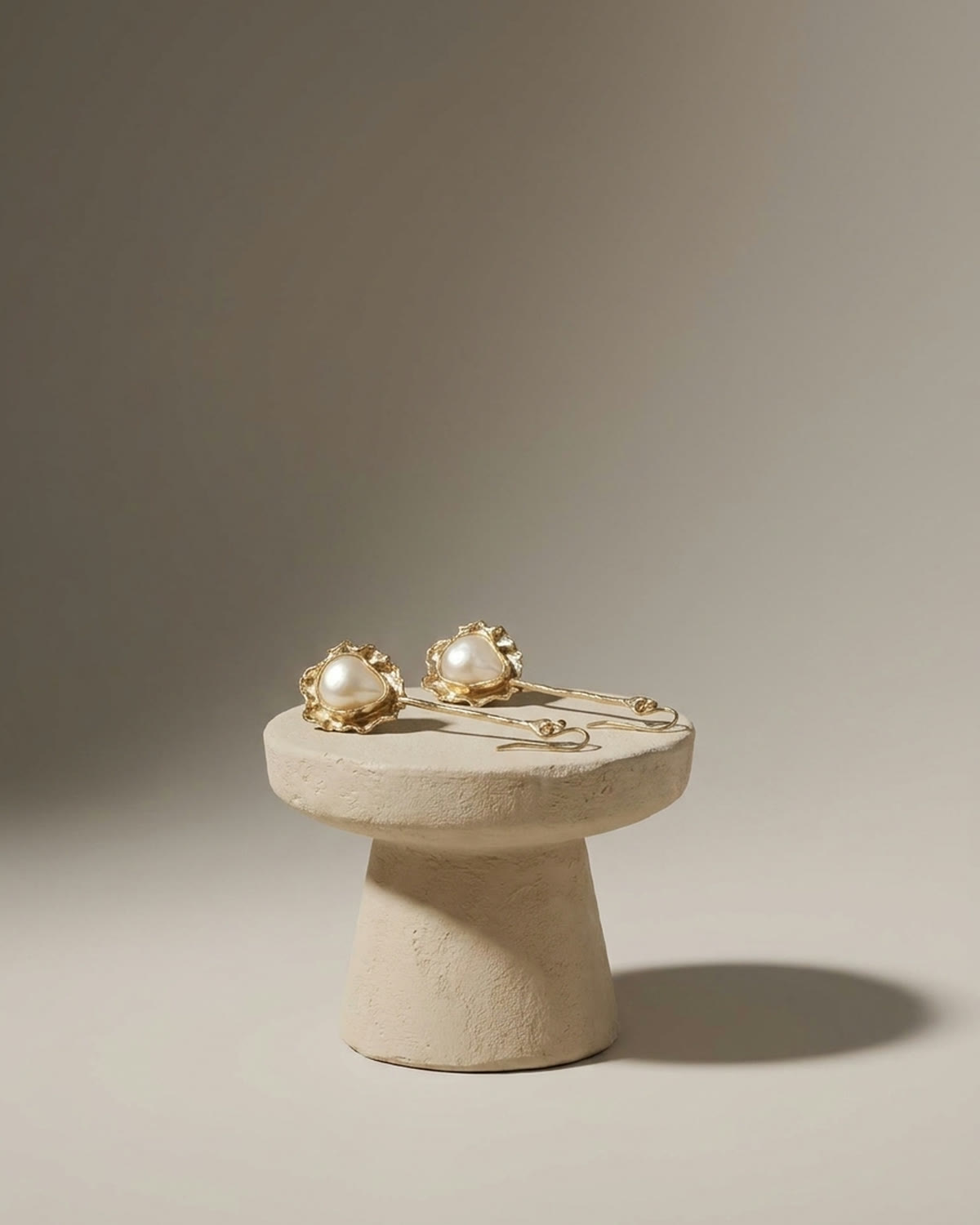 Pearl earrings resting on a white plaster pedestal